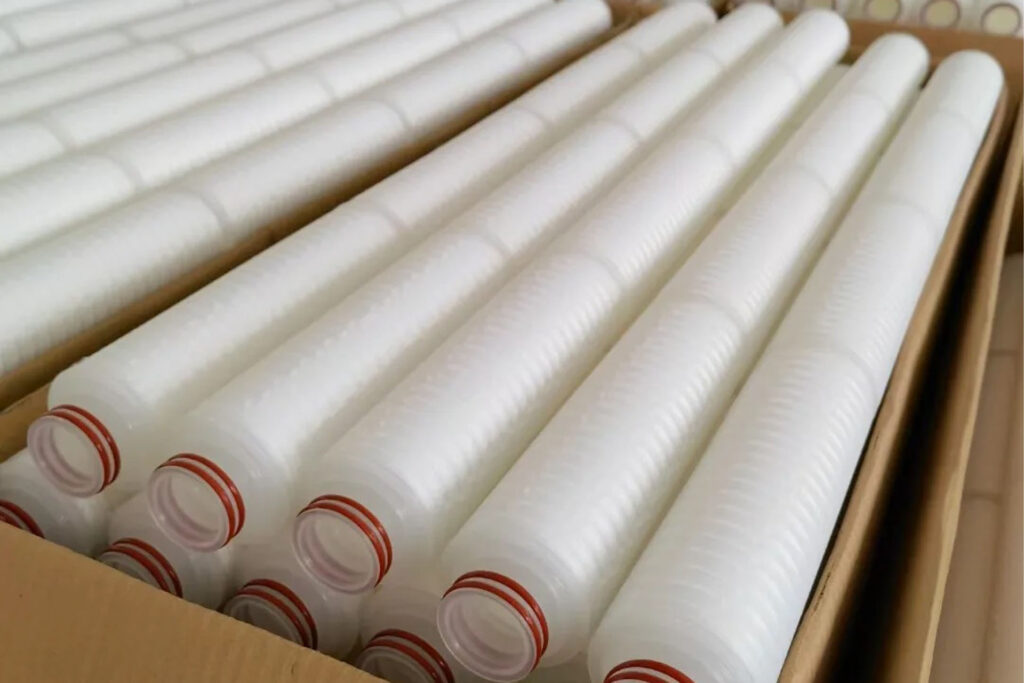 A large-diameter high flow filter cartridge next to several standard cartridges